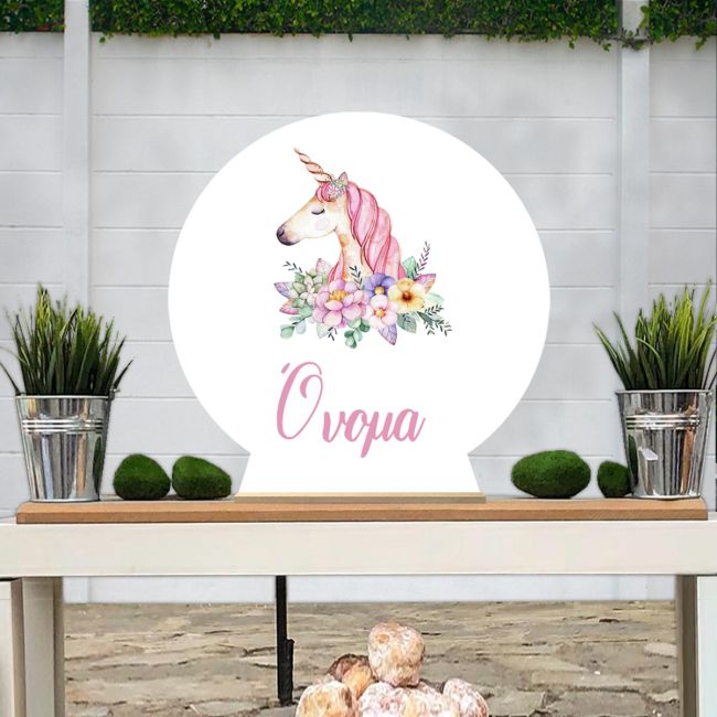 Ξύλινη στρογγυλή πινακίδα, Μονόκερος ακουαρέλα με ζωγραφιστά λουλούδια, με προσαρμοσμένο όνομα, σε τραπέζι.