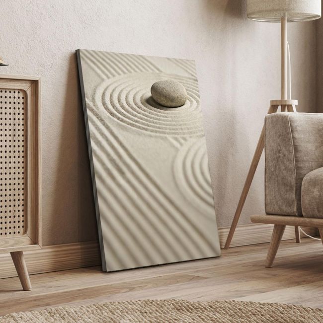 Vertical canvas print: Zen garden with raked sand and single stone. Minimalist art in a modern, light-toned room setting.