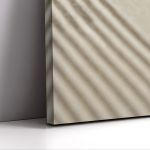 Vertical minimalist canvas print, beige textured with diagonal shadows, leaning on a grey wall, on white surface.