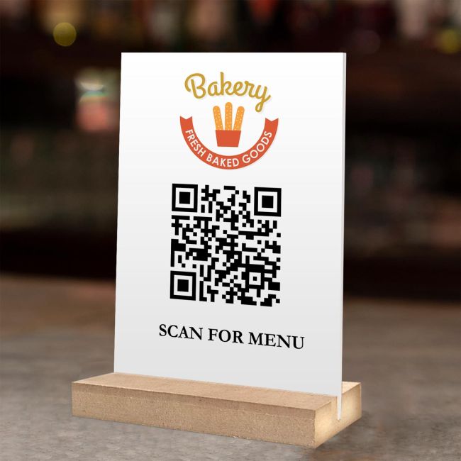 Λευκή πινακίδα QR από plexiglass για μενού, με λογότυπο Bakery σε ξύλινη βάση.