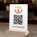 Λευκή πινακίδα QR από plexiglass για μενού, με λογότυπο Bakery σε ξύλινη βάση.