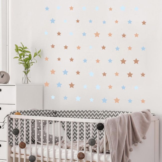 Self-adhesive brown & blue star stickers on white nursery wall above crib, minimalist child decor.