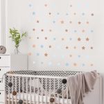 Self-adhesive brown & blue star stickers on white nursery wall above crib, minimalist child decor.