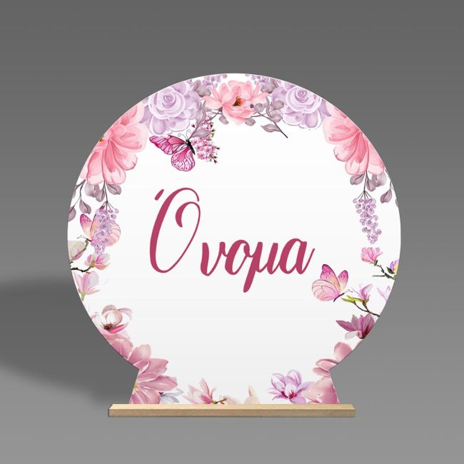 Round wooden candy bar sign on a stand. Features a decorative wreath with pink-purple flowers and butterflies.