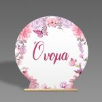 Round wooden candy bar sign on a stand. Features a decorative wreath with pink-purple flowers and butterflies.