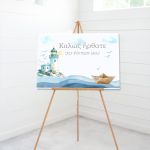 Canvas baptism welcome sign, lighthouse, paper boat 'Ηλίας', waves. On wooden easel, white paneled wall.