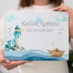 Hardcover guestbook with watercolor lighthouse, paper boat, and waves design for baptism.