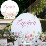 Στρογγυλή ξύλινη πινακίδα candy bar με όνομα Ειρήνη και λουλούδια ακουαρέλας, σε τραπέζι γλυκών.