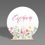 Στρογγυλή ξύλινη πινακίδα candy bar με στάμπα watercolor αγριολούλουδα, ροζ όνομα και ξύλινη βάση.