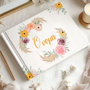 Hardcover guest book, boho yellow, orange, purple, pink flowers, 'Όνομα' script. Held in hands. 2