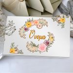 Βιβλίο ευχών με χάρτινο εξώφυλλο, boho στεφάνι κίτρινα/μωβ/ροζ λουλούδια, πούπουλα, "Όνομα". Σε λευκή βάση.