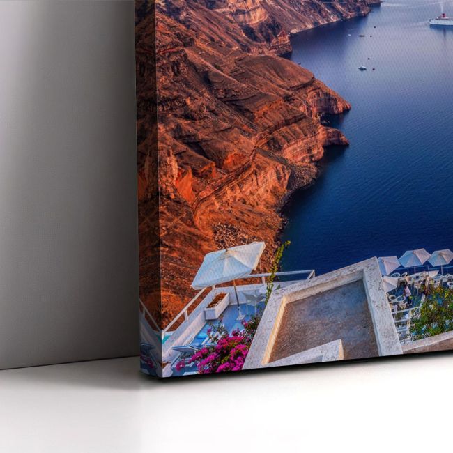 Photographic canvas, Santorini twilight with volcanic cliffs, deep blue sea, white architecture. Displayed on grey wall.