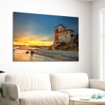 Canvas print: Sunset at Ouranoupolis Tower, Chalkidiki. Displayed on white wall, above sofa.
