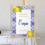 Πίνακας βάπτισης κάθετος, μπλε πλακάκια & λεμόνια σε καμβά με ξύλινη κορνίζα, σε φυσικό ξύλινο καβαλέτο, σε τοίχο.
