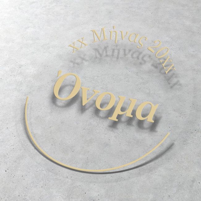 Transparent circular baptism sticker with gold 'Name' and date text, on a grey textured surface.