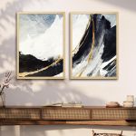 Diptych canvas art with abstract mountains and golden lines, on wall above wooden furniture.