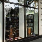 Λευκό αυτοκόλλητο βιτρίνας με ιστούς αράχνης και αράχες σε γωνίες βιβλιοπωλείου για το Halloween